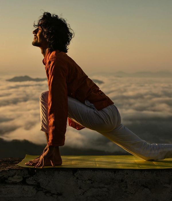 Silhouette of a man stretching against a sunrise, feeling energized.